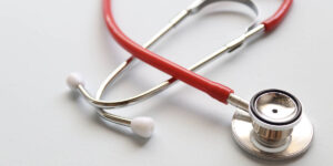Red stethoscope on white background.