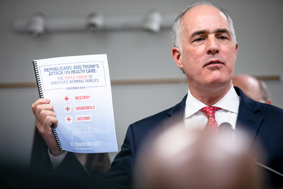 Sen. Casey holding a report while speaking about Pennsylvanians signing up for the Affordable Care Act