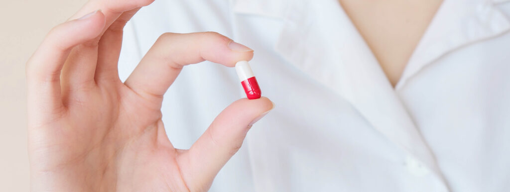 Pharmacist holding a red and white pill capsule